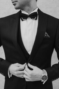 Man examining the stitching, fabric, lining, and fit of a well-constructed suit in a fitting room.