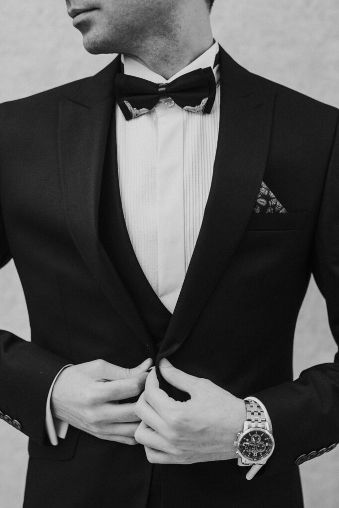 Man examining the stitching, fabric, lining, and fit of a well-constructed suit in a fitting room.