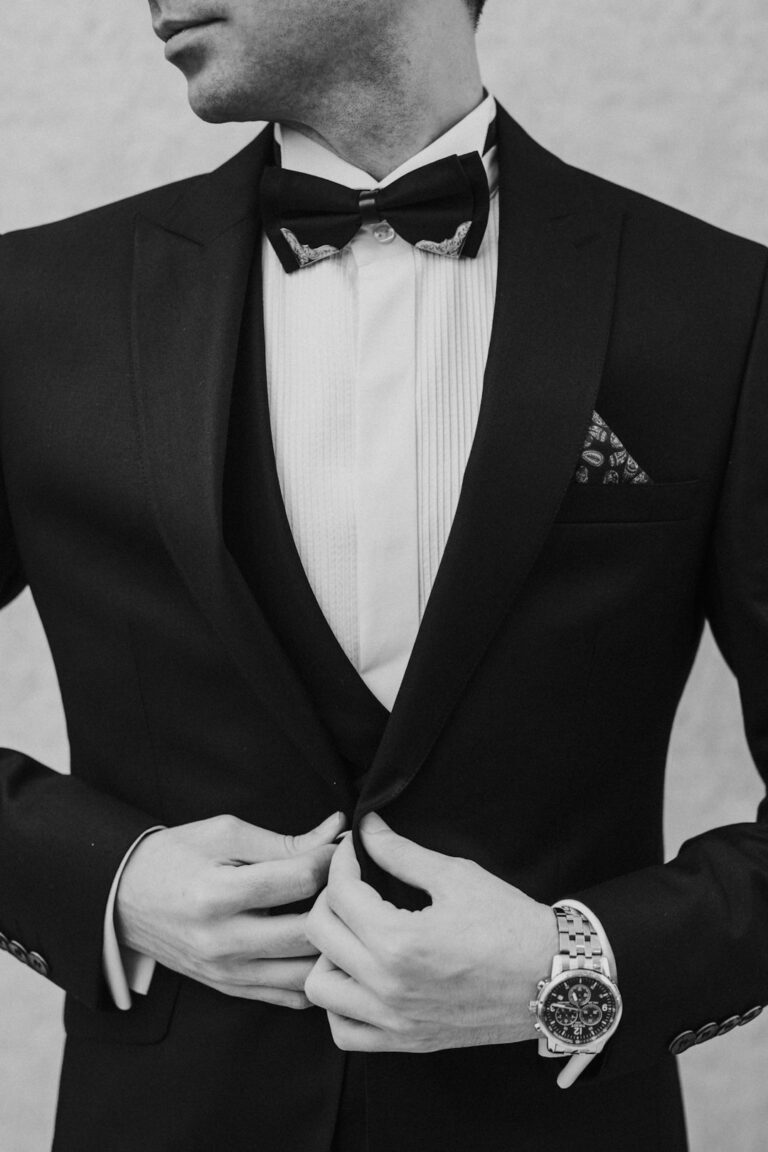 Man examining the stitching, fabric, lining, and fit of a well-constructed suit in a fitting room.